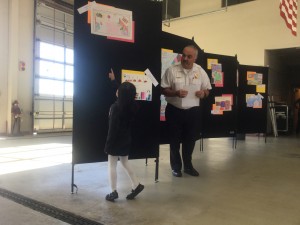 Fire Marshall Luis Da Silva invites a student to explain her winning poster to the group