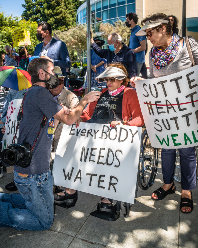 A man kneeling in front of a woman who is holding a placard