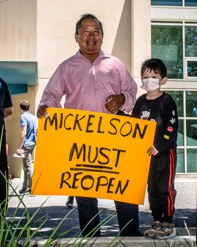 A man and a child holding a yellow placard