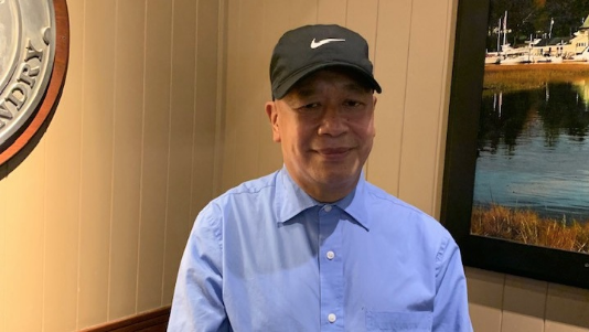 Nemesio Isorena: a man in a blue collared shirt and black cap