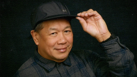 Nemesio Isorena: a man in a plaid collared polo and black cap