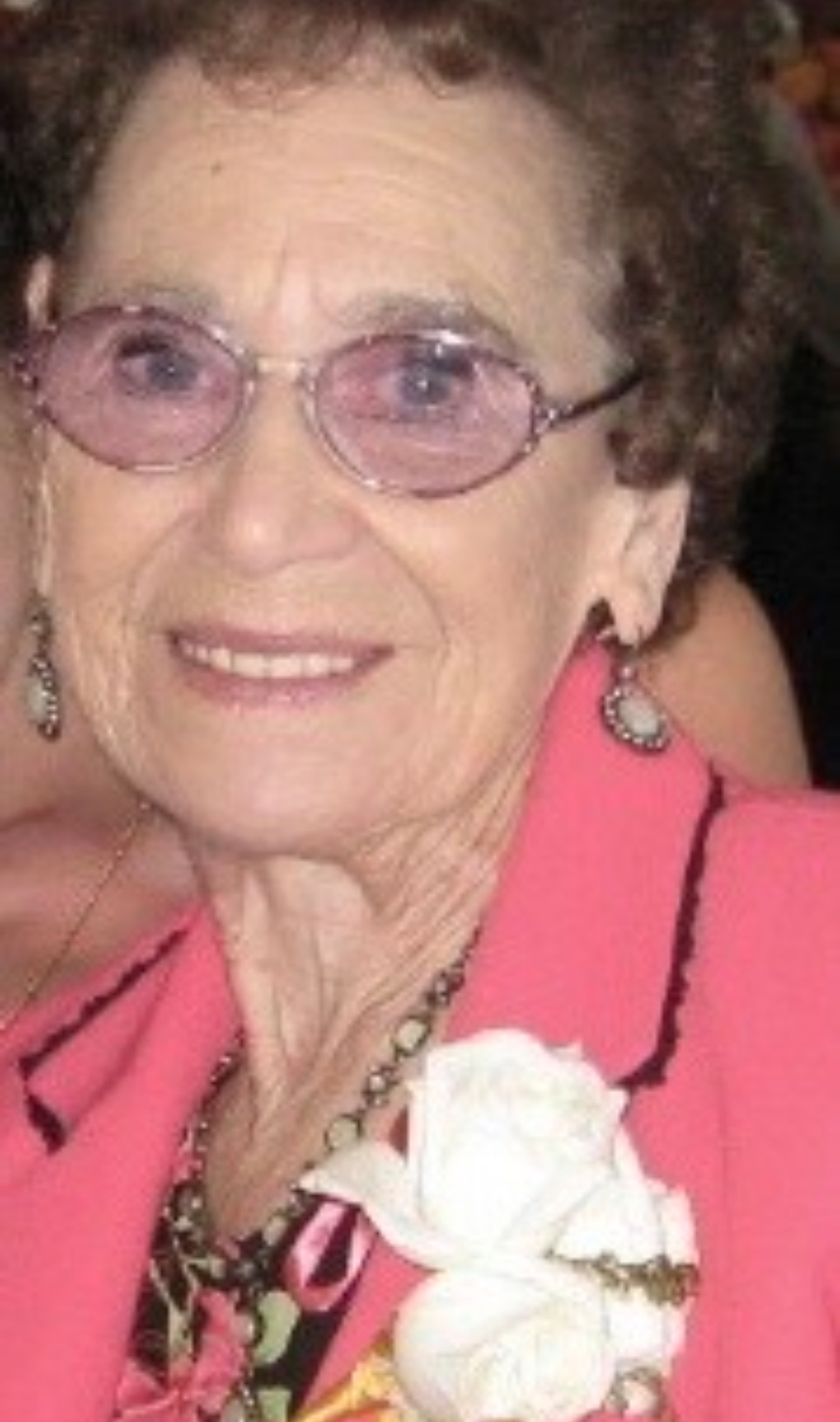 An elderly woman in a pink and pink-tinted glasses