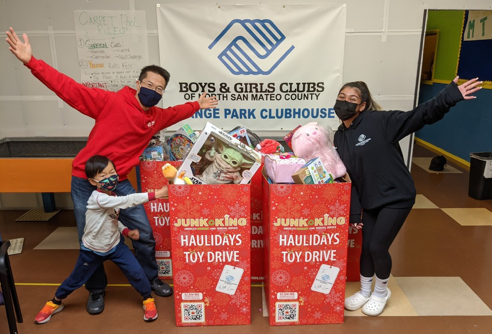 A man, a woman, and a child posing for a picture with the boxes of toy donations