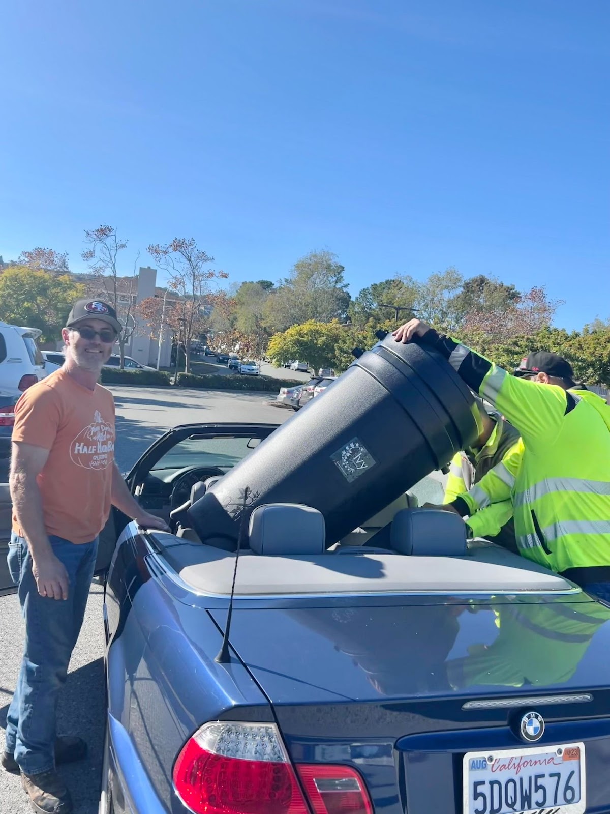 A San Mateo County resident poses as his rain barrels are loaded into his car.